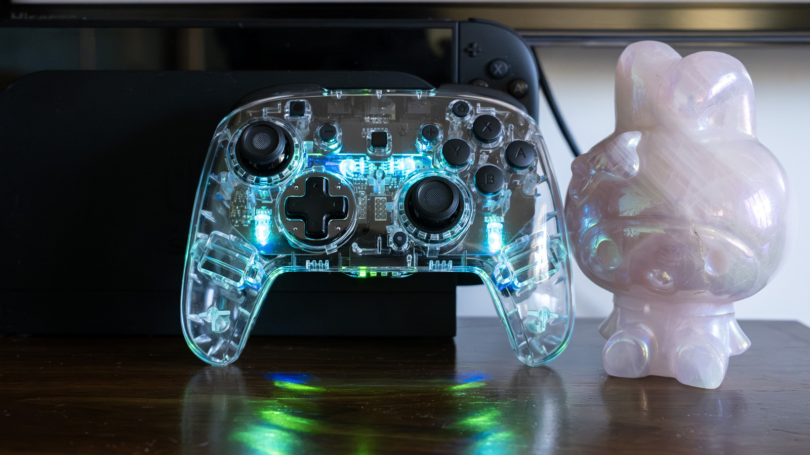 O Turtle Beach Afterglow Wireless Controller para o Nintendo Switch 2 acaba de roubar a cena, e é um presente para quem quer que o setup inteiro brilhe. Envolvido em um corpo transparente que parece uma gema na mão, o controle oferece quatro modos de iluminação RGB ajustáveis na hora, de brilhos fixos a cores que reagem a cada movimento do analógico.

Por baixo do visual, o hardware acompanha. Os analógicos TMR prometem precisão de longo prazo sem drift, o alcance sem fio chega a cerca de 9 metros e a bateria dura em torno de 40 horas sem as luzes ligadas, ou aproximadamente 12 horas com os efeitos a todo vapor. Botões com clique firme, gatilhos acolchoados e paddles traseiros remapeáveis completam uma experiência confortável e de baixa latência para sessões longas.

Por 65 dólares, ele fica abaixo do Switch 2 Pro Controller oficial e costuma aparecer ainda mais barato em promoções. As concessões existem: não há vibração ou háptica e ele não liga o console sozinho, além de alguns botões pequenos serem difíceis de ler de relance. Ainda assim, para quem quer analógicos sem drift e um show de luz translúcido nas mãos, o Afterglow se destaca.