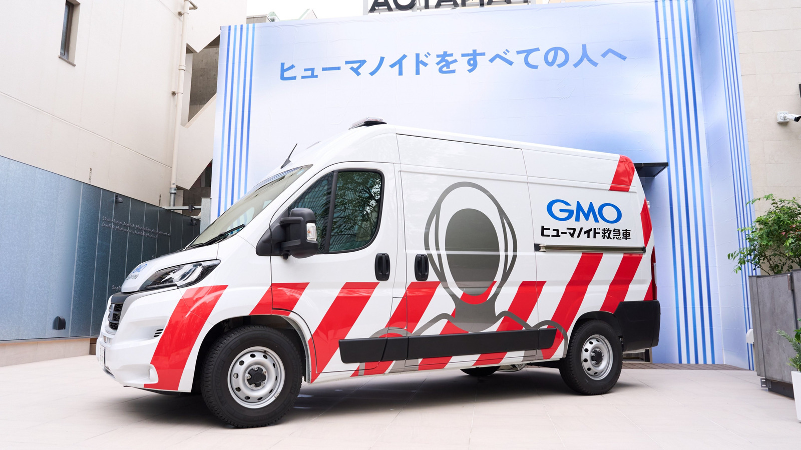 Tóquio acaba de ganhar um serviço que parece ficção científica: uma ambulância para robôs humanoides. O GMO Internet Group está colocando nas ruas uma van de manutenção equipada com aparelhos de diagnóstico, peças de reposição e engenheiros, pronta para socorrer qualquer humanoide que pare de funcionar, com um robô reserva a bordo para assumir o posto na hora.

O veículo, desenhado por Yasumichi Morita com barras de luz roxas e os dizeres humanoid ambulance, é o primeiro do tipo no Japão. As unidades quebradas são levadas de volta ao Humanoid Lab, em Shibuya, para reparos mais profundos, um sinal claro de que as máquinas já são tratadas como força de trabalho que precisa de manutenção, corpos extras e assistência na estrada.

Por enquanto é uma frota mínima, com uma única van atendendo os robôs da própria GMO AIR, mas a ambição é gigantesca. O governo japonês quer mais de 30 por cento do mercado global de robótica até 2040, e a GMO está acumulando experiência de campo agora para escalar no momento em que os humanoides forem tão comuns quanto caminhões de entrega.