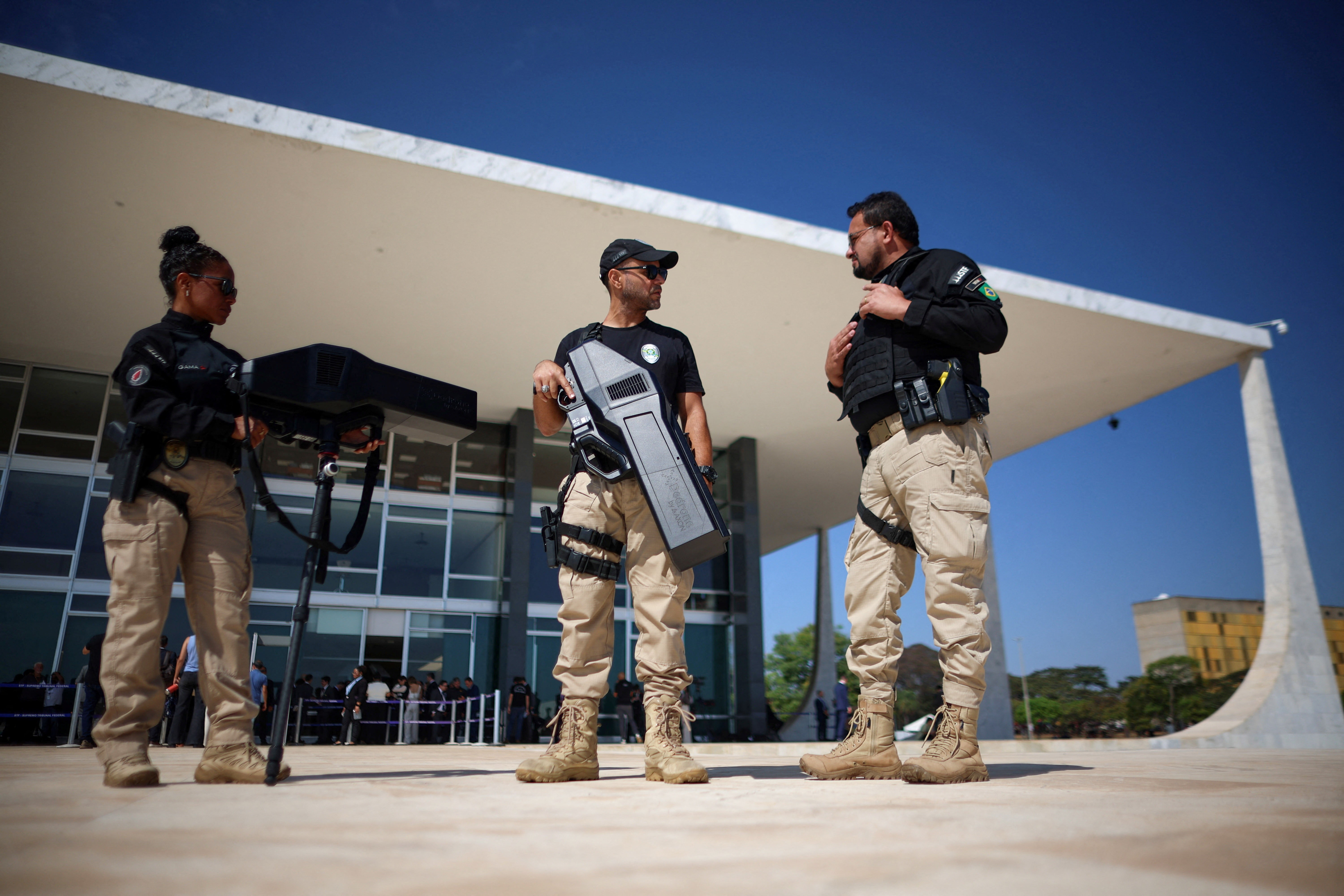 O STF mobilizou uma arma antidrone de aparência futurística durante um julgamento histórico, e a tecnologia por trás dela parece coisa de ficção científica. Com antenas direcionais integradas e um painel de controle com áudio e sensor óptico, o dispositivo eleva a defesa contra drones a um novo patamar.

Um dos modelos mais famosos é o DroneGun Tactical, com design de rifle e operação feita com as duas mãos. A tecnologia identifica drones por frequência e ondas de rádio e, ao localizar um alvo suspeito, emite um sinal que interrompe o contato com o controle original. A partir daí, o agente de segurança assume o comando, desvia e pousa o drone em local seguro para inspeção, ou força o equipamento a voltar exatamente ao ponto de onde decolou.

O mesmo tipo de aparato já é usado em presídios de São Paulo para impedir que drones levem celulares e drogas aos detentos, um sinal claro de como a segurança por bloqueio de sinal virou ferramenta essencial em operações de alto risco.