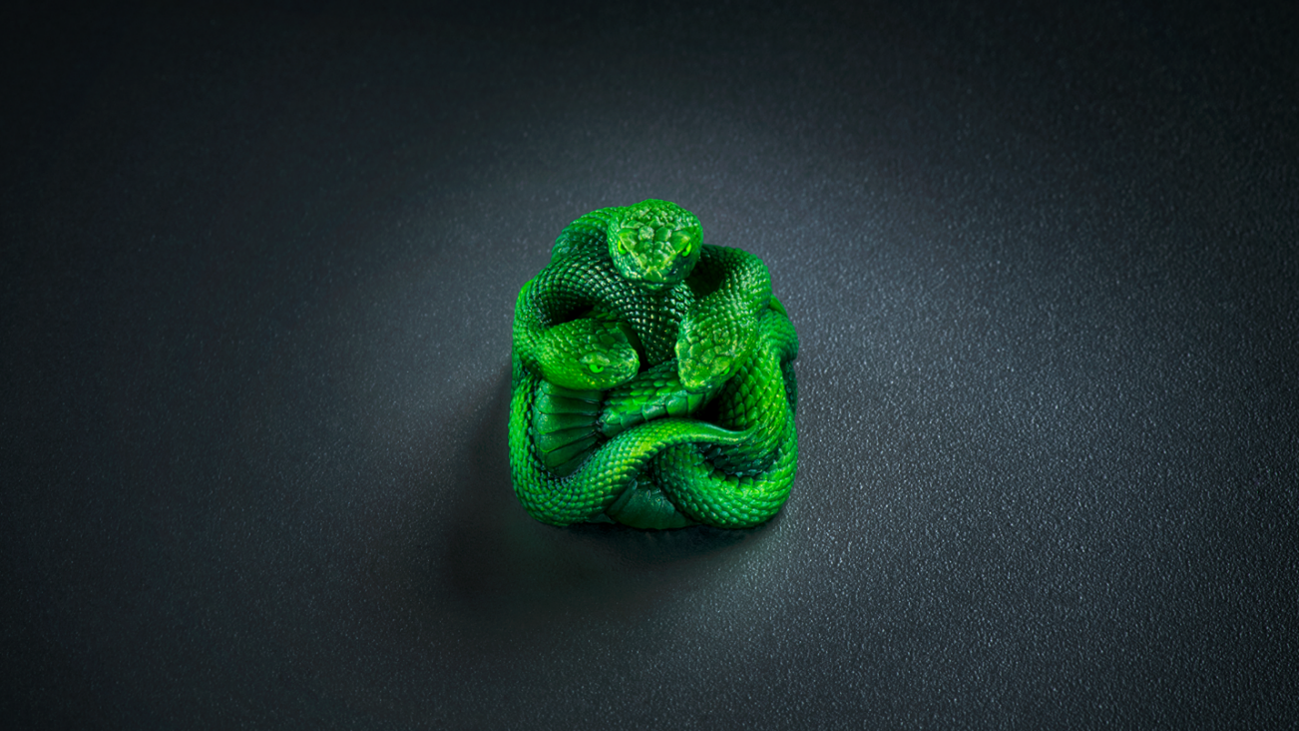 Prepare-se, fãs da Razer. A marca acaba de apresentar a Razer Artisan Keycap - Triple-Headed Snake Edition, a primeira keycap com acabamento finalizado à mão e um verdadeiro divisor de águas na personalização de teclados. Não é só uma tecla: é uma obra de arte em miniatura, esculpida em 3D e pintada à mão para homenagear a lendária serpente de três cabeças que acompanha a Razer há mais de duas décadas.

Cada peça passa por um processo rigoroso: modelagem 3D de precisão, construção em resina moldada com cores vibrantes e resistentes ao desbotamento, pintura individual à mão e um controle de qualidade em duas etapas que garante que apenas peças impecáveis cheguem até você. A keycap é compatível com switches de haste cruzada, encaixando com segurança na maioria dos teclados Razer e em outros modelos compatíveis.

Produzida em quantidades altamente limitadas e disponível exclusivamente pela Razer, essa edição é para quem vive e respira a marca. Ainda não há previsão de preço para o Brasil, mas se você quer garantir esse item de colecionador, o tempo está correndo.